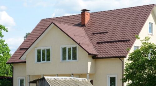 Dormer windows on metal roof. A house with a roof made of metal roofing with mansard windows and rain gutter. Metal Roofing