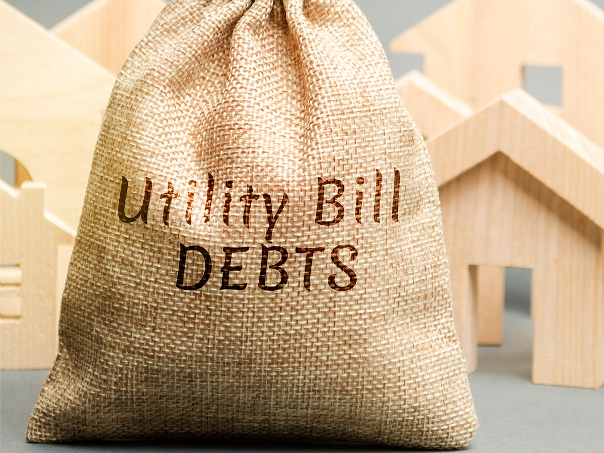 1200x900GMB-4 A burlap bag labeled with the words “Utility Bill Debt.”